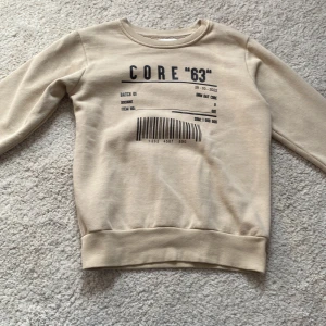 Beige tröja med svart text på  - Beige tröja med svart text på i storlek 134/140 