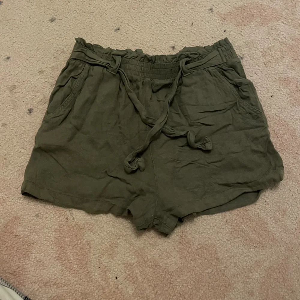 Ett par olivgröna shorts som jag har använt dem mycket med de är fortfarande i väldigt bra skick de är bara lite skrynkliga men det kan man styka om man vill de är väldigt sladriga vilket jag tycker är skönt för det sitter inte stelt på kroppen . Shorts.