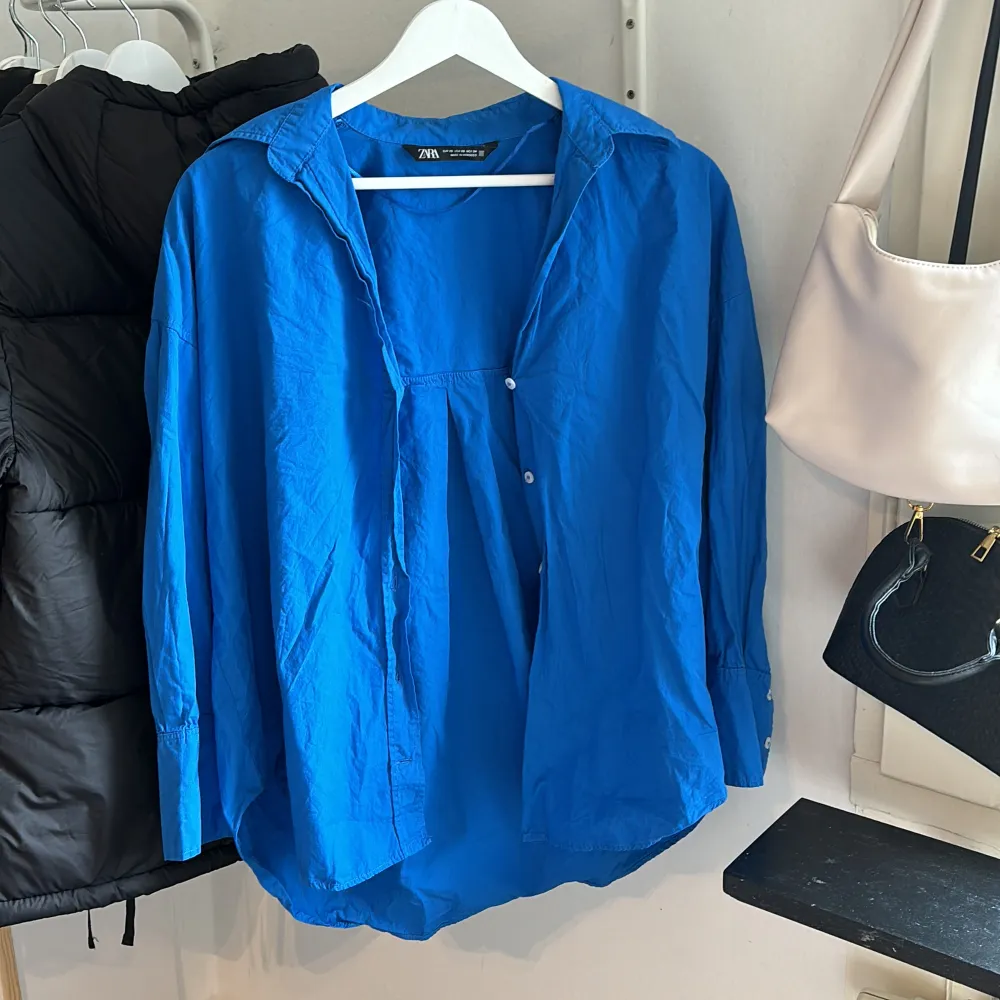 Blå skjorta från Zara i storlek xs. Väldigt fin till sommaren, går att öppna till en kofta. Det finns knappar längs ut vid armarna som också går att öppna. Har använts en gång (nyskick). Passar dig som är mellan xs-m (100% bomull) . Skjortor.