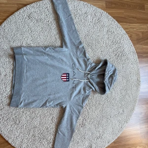 Hoodie - En grå Gant hoodie. Tröjan är i ett väldigt bra skick då den endast är använd en gång. Tröjan anger ingen storlek men jag skulle säga att den är i storlek M. 💗💗