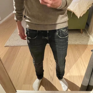 Replay Anbass jeans - Ett par svarta Replay Anbass jeans i storlek 28 32.  Finns två små skador som är ihopsydda men det bidrar till den slitna looken på jeansen. Jag kan skicka bild på skadorna om det önskas. Inte använda på ett tag.