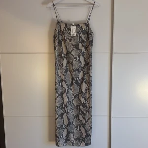 Satinklänning från HM strl S, Lappen kvar!! - Lång satinklänning i ormmönster från HM strl S 🐍 Oanvänd, lappen kvar!!