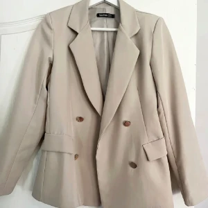 Beige kavaj - Beige kavaj med guld knappar från Boohoo. Storlek 36. Använd 1 gång