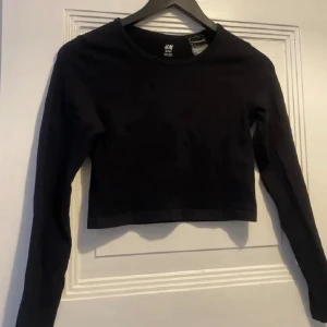 Croppad träningstopp - Croptopad träningsskjorta från H&M. Använd ett fåtal gånger.