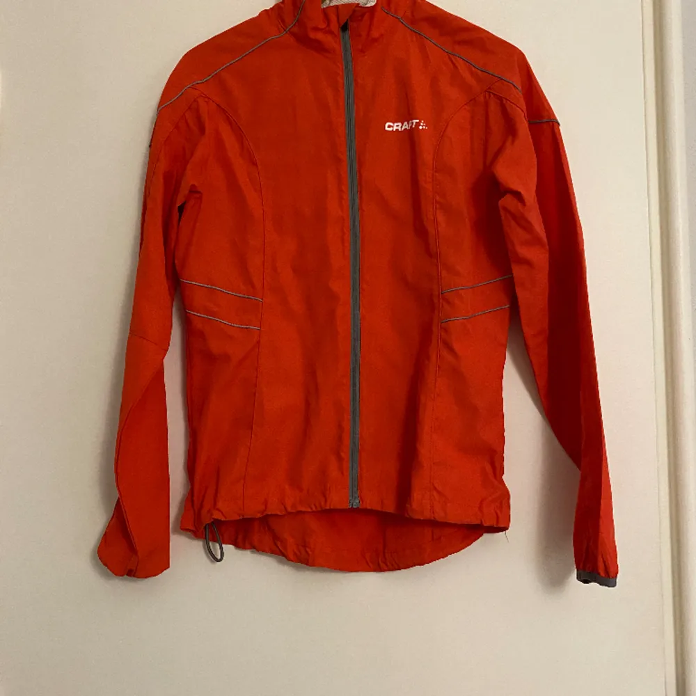 Träningsjacka från Craft, orange/grå. Liten fläck vid nacken, men går säkert bort i tvätten. Dragsko så du kan välja om du vill ha den kortare.. Hupparit & Collegepaidat.