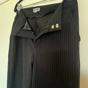 Kostymbyxor  - Ett par svarta kostymbyxor med vita ränder från Madlady i stl.36.  Sitter väldigt snyggt på kroppen, bra passform. De är i bra skick! 