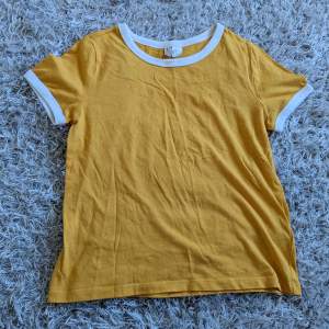Säljer denna gula T-shirt från H&M/Divided då den inte används. Den är ganska ur-tvättad och den har en pytteliten vit 