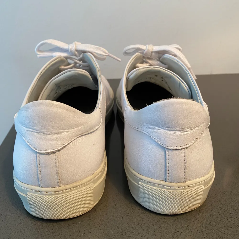 Axel Arigato clean 90 läderskor i strl 42.  Skorna har endast använts under förra sommaren. De har några repor på skorna samt att det finns ett hål på insidan av skon vid hälen.  Kommer från ett djur och rökfritt hem.. Skor.