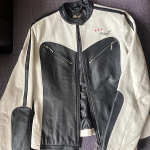 Petroff Skinnjacka - Snygg Petroff skinnjacka i svart och vitt läder, racer-modell.  Två sidofickor och en innerficka. Storlek 38. 