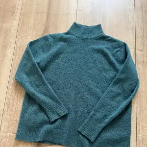 En grön stickad ylle liknande tröjja i storlek S/M