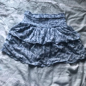 Blå sommrig och blommig kjol - Säljer denna jättesöta ljusblå kjolen då jag inte använder den längre. Den är perfekt till sommaren och har inbyggda shorts! Eftersom det är mycket stretch runt midjan passar den nästan vem som helst.