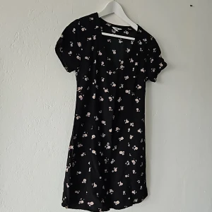 Kortärmad blommig klänning - Kortärmad blommig klänning från Vans, med djup urringning fram. Använd endast ett par gånger