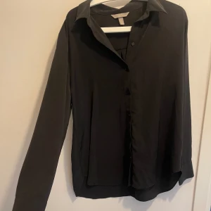 Svart Skjorta H&M - Svart Skjorta i Skönt material  Bra avstånd för knappen där den hamnar på ”bröstet ”. 