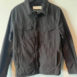 Casual Friday Overshirt/Tunn jacka Svart med Knappar - Svart overshirt/jacka från casual friday   Tunn vår/höst jacka med knappar   Skicket är bra förutom en saknad knapp (3dje ner se första bilden)