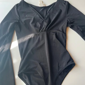 Svart body storlek xs - Svart glansig omlottbody från H&an i storlek xs. 