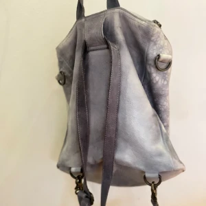 UNmade Copenhagen ryggsäck i läder - Grå-melerad med dragkedja. Två mindre fläckar upptill, inte testat att smörja med lädermedel. Oskadad annars, fint skick. 