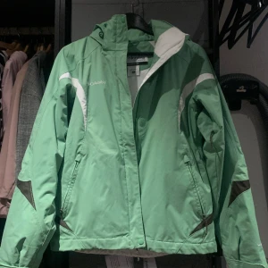 columbia grön skid/vinterjacka - Köpte på tradera men passa inte som jag ville. Skidjacka/Vinterjacka från Columbia i Storlek S, nyskick med snölås, avtagbar luva o ventilationsnät under armarna. Mäns storlek men passar unisex.  Längd: Fram 60cm Bak: 63cm Bredd: över bröstet: 50cm 