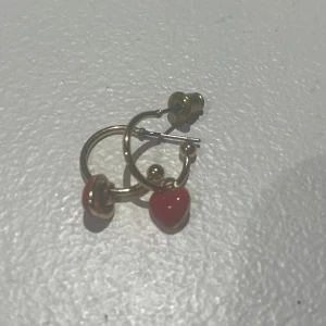 Örhänge  - Guldfärgade örhängen med röda hjärtan.