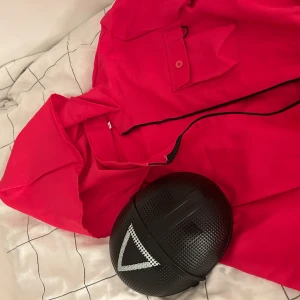 Squidgame kostym och mask - Squidgame kostym och tillhörande mask. Kostymen är i storlek s! Köparen står för frakt. Skriv privat om det är något som ni undrar!