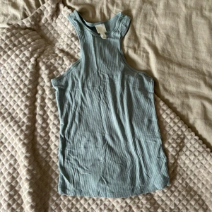 Ljusblå ribbad linnetopp från H&M - En ljusblå ribbad linnetopp från H&M. Toppen är ärmlös och har en rund halsringning. Helt oanvänd men har endast tagit bort etikett. 