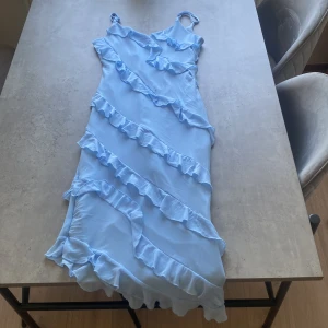 Klänning med volanger  - Klänning med volanger  Aldrig använd  Ganska tjockt tyg 