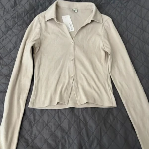 Beige kofta från NLY Trend - En oanvänd beige kofta från NLY Trend med långa ärmar och knappar framtill. Koftan har en ribbad struktur och en krage.💕