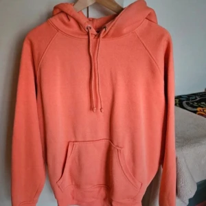 Korallfärgad hoodie - En jättefin korallfärgad hoodie från Bikbok i storlek S Använd några gånger men fortfarande i bra skick dock lite små noppror men inget man tänker särskilt mycket på Skriv om ni har frågor, vill ha fler bilder eller har prisförslag🧡