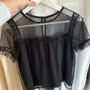 Svart blus - Svart blus med volanger i prickigt mesh-tyg från jacqueline de young, storlek M💞