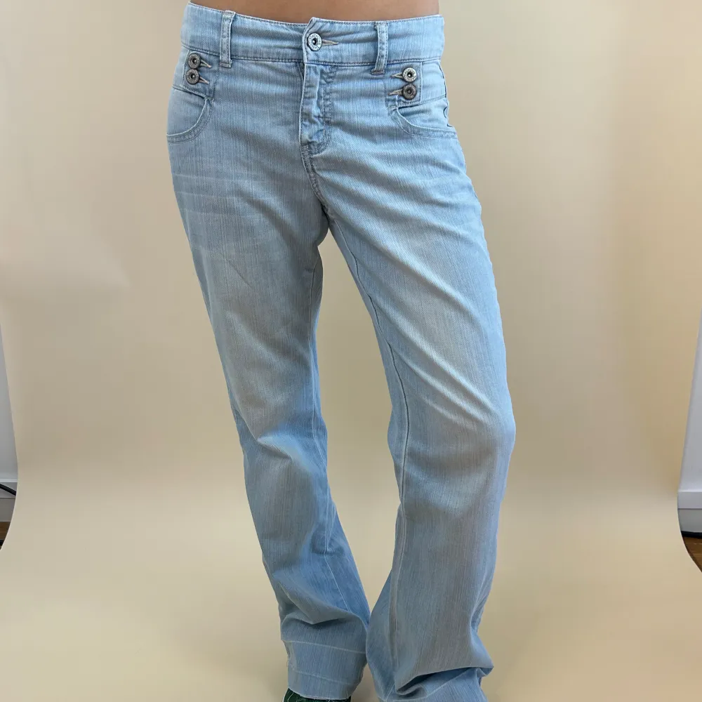 Midjemåttet är 85cm och innerbenslängden är 80cm Raka/utsvängda lågmidjade jeans med coola detaljer vid midjan och bakfickorna. Uppsprätta där nere för att göra dom längre! Modellen är 165cm. Jeans & Byxor.