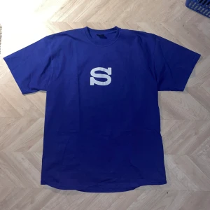 Stüssy T-shirt 1904594 - Blå t-shirt från Stüssy i nyskick, stil 1904594, storlek XL, passar bra på mig som är 181 cm lång och väger 85 kg. Säljes i befintligt skick.