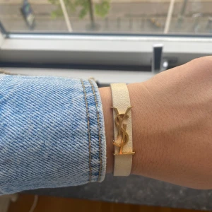 Ysl armband - Vitt/beiget ysl armband i nyskick!! Fick i födelsedagspresent och säljer då det inte kommer till användning💕💕