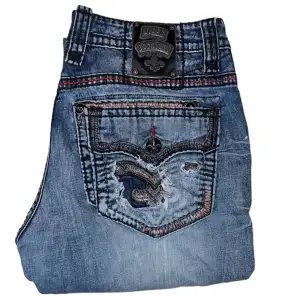 Rock Revival jeans Bootcut fit. W36. Har fläckar på framsidan syns på andra bilden. Därav pris. [Ytterbenslängd 103cm] [Innebenslängd 76cm] [Midja 46cm] [Benöppning 24cm]