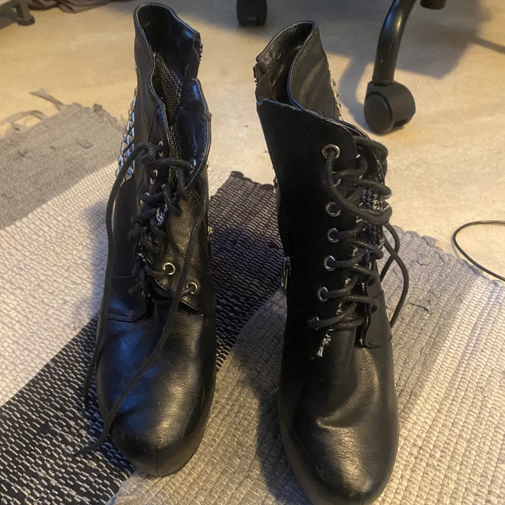 Svarta boots med små metall taggar på . Skor.