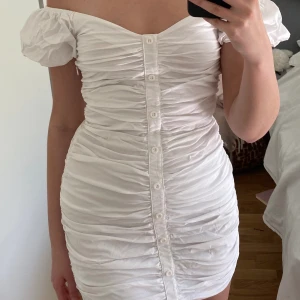 Vit klänning - Säljer denna supersöta vita miniklänningen. Det är från Gina Tricot och är i storlek 34. Kan bäras både off och on shoulder. Fin till studenten eller nu till sommarn🫶🏼.