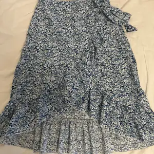 En blå blommig kjol som når vid knäna med en liten slit som går upp för knät några cm. Den är köpt på shien i strl xs o passar toppen. Använd cirka 2 ggr. 