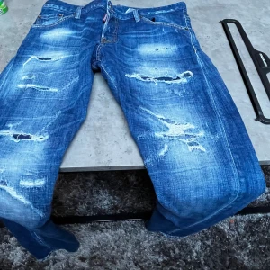 DSQ2 blåa jeans Ripped, sexy twist - Hej! Säljer mina DSQ2 jeans då dom tycärr ej används längre och samlar mest damm, dom är enbart tvättade 1 eller 2 gånger och varit hänga resten av tiden.  Storlek: 50 Att nr: DSQ2 s74LB1265   FINNS kvitto, påse, extra knappar, DSQ2 jeans hängare