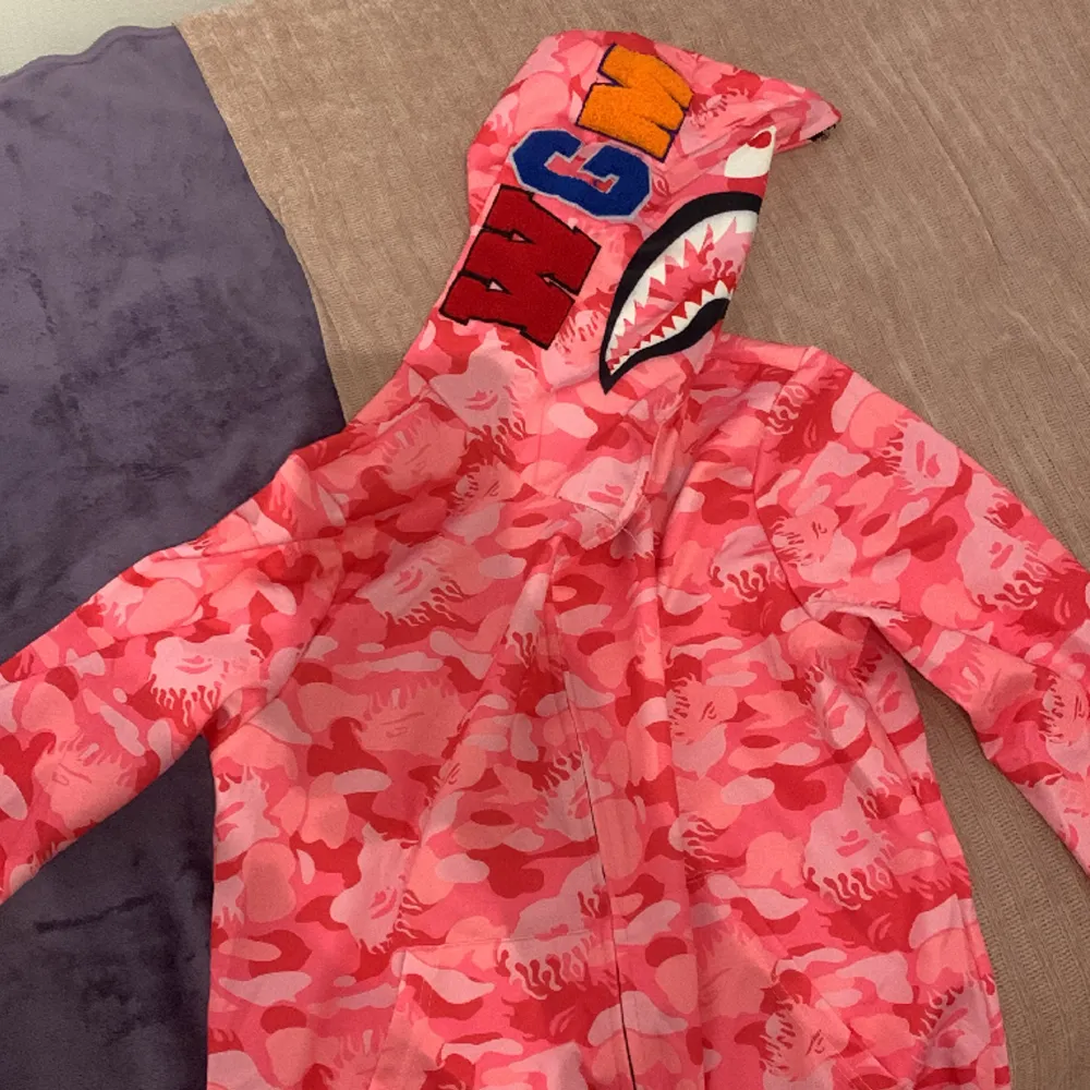 Rosa bape zip up hoodie med zip ända upp till luvan, 3D bokstäver på luvan. Storlek s-xs unisex. Aldrig använd!. Hoodies.