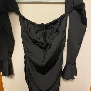 Svart klänning - En svart fin off shoulder klänning med volang i ärmarna och knyte vid bröstet, kort till över knäna, fin till fest eller sommar