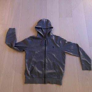 Polo Ralph lauren zip hoodie  - Grå polo Ralph lauren hoodie i storlek M. Tröjan är i perfekt skick utan fläckar eller defekter. Köpt för 1400. Hör av dig vid minsta lilla!👊