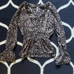 Leopard blus - Fin leopard blus! Den saknar tyvärr en knapp längst ner och har ett litet hål på baksidan men som knappt syns. Färger ser man bäst på sista bilden. Materialet ser man också bäst på sista bilden och det är lite genomskinligt!