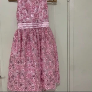 Klänning - Kort rosa barn klänning. Köpt i USA i storleken 16.  Pris: 600   Skicka meddelande om du vill ha flera bilder på klänningen. Kan mötas i Södertälje eller så kan den fraktas.