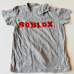 Roblox T-shirt ifrån Lager 157. Storlek 130.  Har ett litet hål vid ”O”.  Bokstäverna är något lösa här och där.  