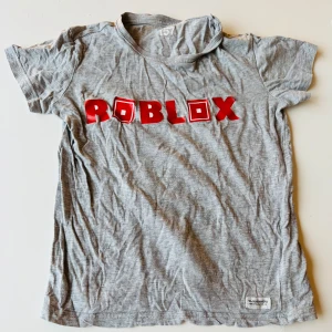 Roblox T-shirt ifrån Lager 157. Storlek 130. - Roblox T-shirt ifrån Lager 157. Storlek 130.  Har ett litet hål vid ”O”.  Bokstäverna är något lösa här och där.  