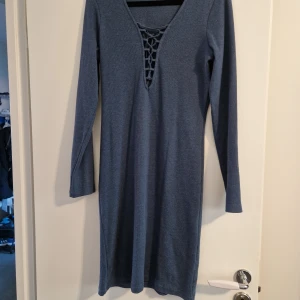 Knälång klänning  - Klänning som är knälång. Har snörning vis bysten.