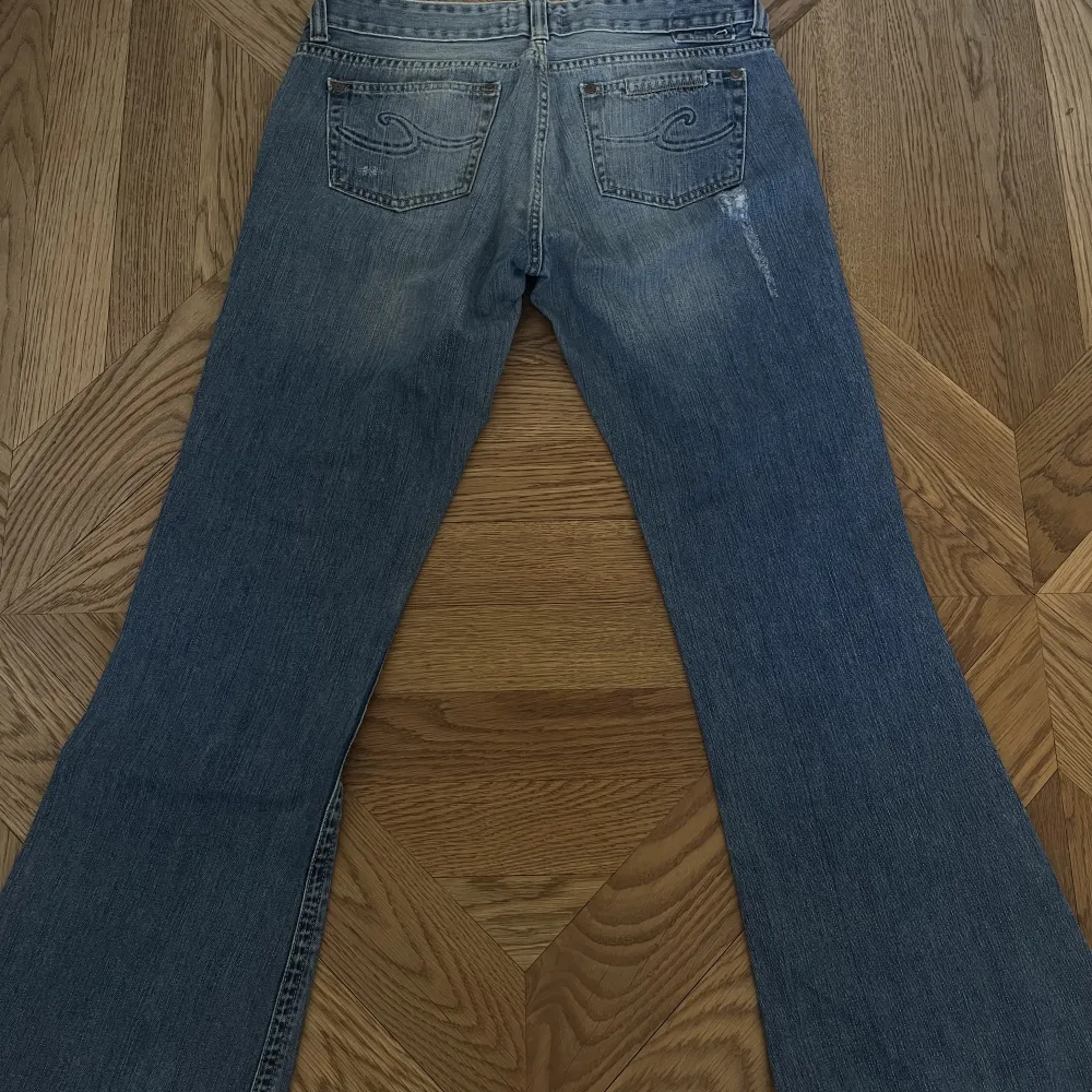 Jättecoola bootcut jeans som är lite baggie med lite slitningar och coola fickor. Finns en liten fläck som syns på tredje bilden men ingen stor.. Jeans & Byxor.