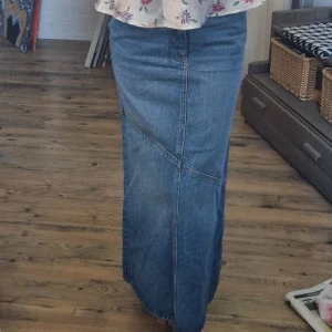 Jeanskjol - Lång lågmidjad jeanskjol. Klippt en slits vid fötterna där bak för att få lite mer utrymme när man går (skickar givetvis bild)