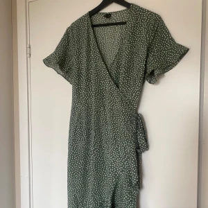 Omlott klänning - Grön omlottklänning med vita prickar från Veromoda. Slutar lite över knäna och är prefekt till sommaren. Klänningen är i fint skick