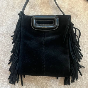 liten Maje väska - Så cool svart Maje väska i den lilla modellen. Materialet är mocka. Väldigt fint skick, väldigt sparsamt använd! Dustbag medkommer. Nypris: 2700kr.  Mycket bra skick endast liten nopprig men går nog att borsta bort med mockaborste. 💕Skriv vid frågor!
