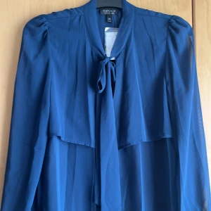 Långärmad blus  - Diesel färgat långärmad lätt blus med knappar och knyt på framsidan volang på ryggen. Tunn fin tyg, klassisk modell lätt genomskinlig. Helt ny med prislappen på.