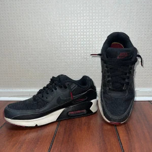 Nike airmax 90 - Använda men ändå i bra skick. Populära skor. Storlek 38.5. Svarta med röda detaljer.